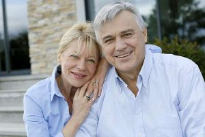 Elderly couple in front of house.