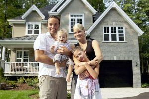 Home ownnership advantages. Happy family in front of house.