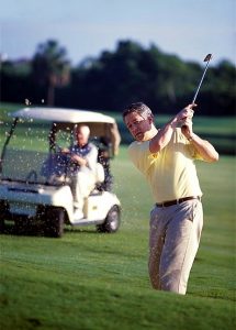 Man swinging club on golf course.